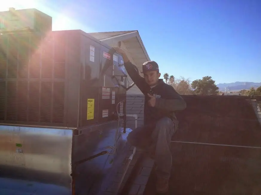HVAC technician performing Air Duct Cleaning on a rooftop unit in Kirby